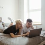 a couple using a laptop on a bed